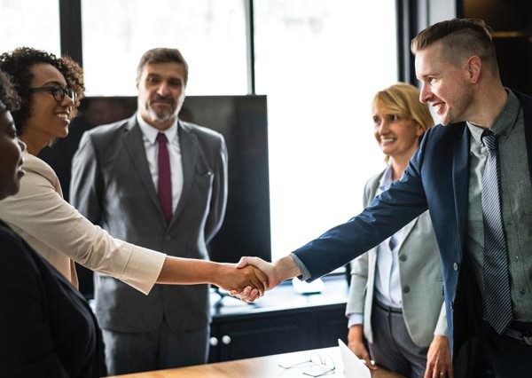 a business meeting of four people smiling and shaking hands