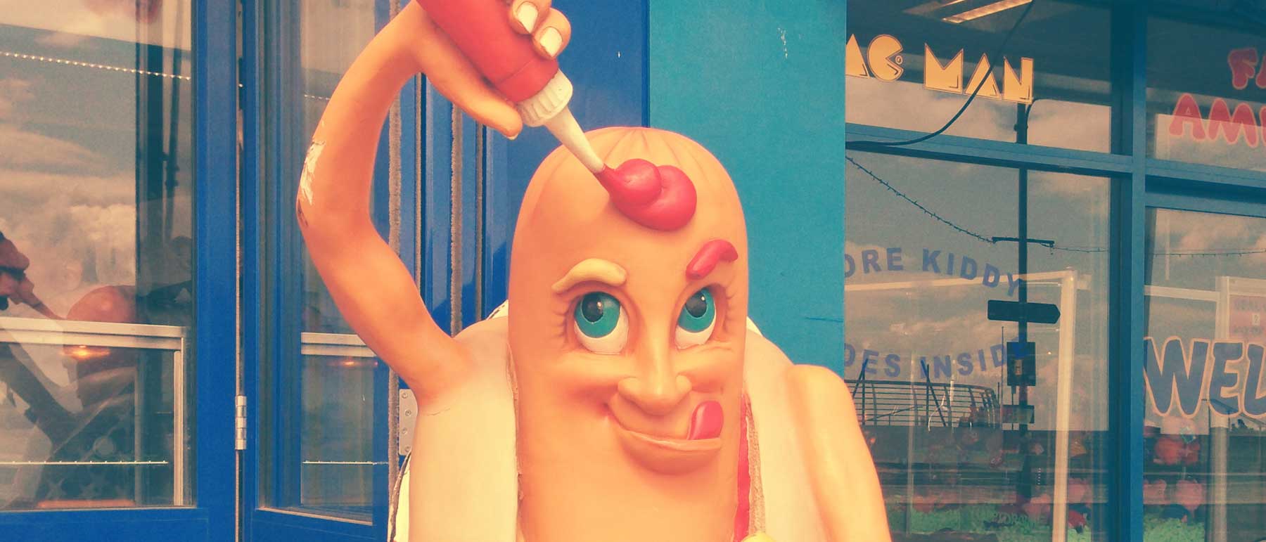 cartoon hot dog statue pouring ketchup on itself